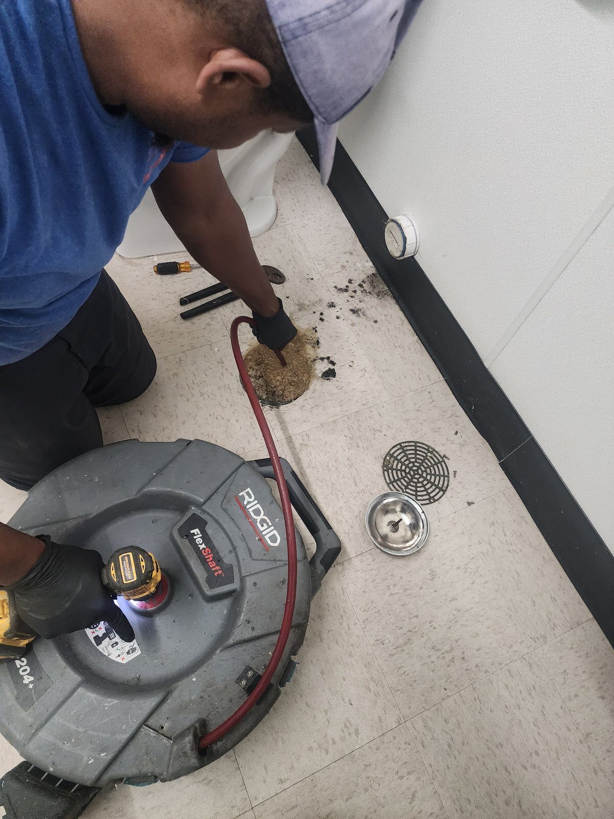Plumber cabling a blocked drain line through a floor cleanout