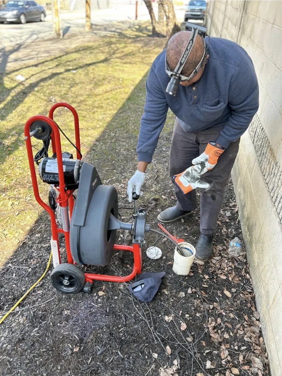 Fitzroy of Day to Day Plumbing running a drum machine at an outdoor sewer cleanout