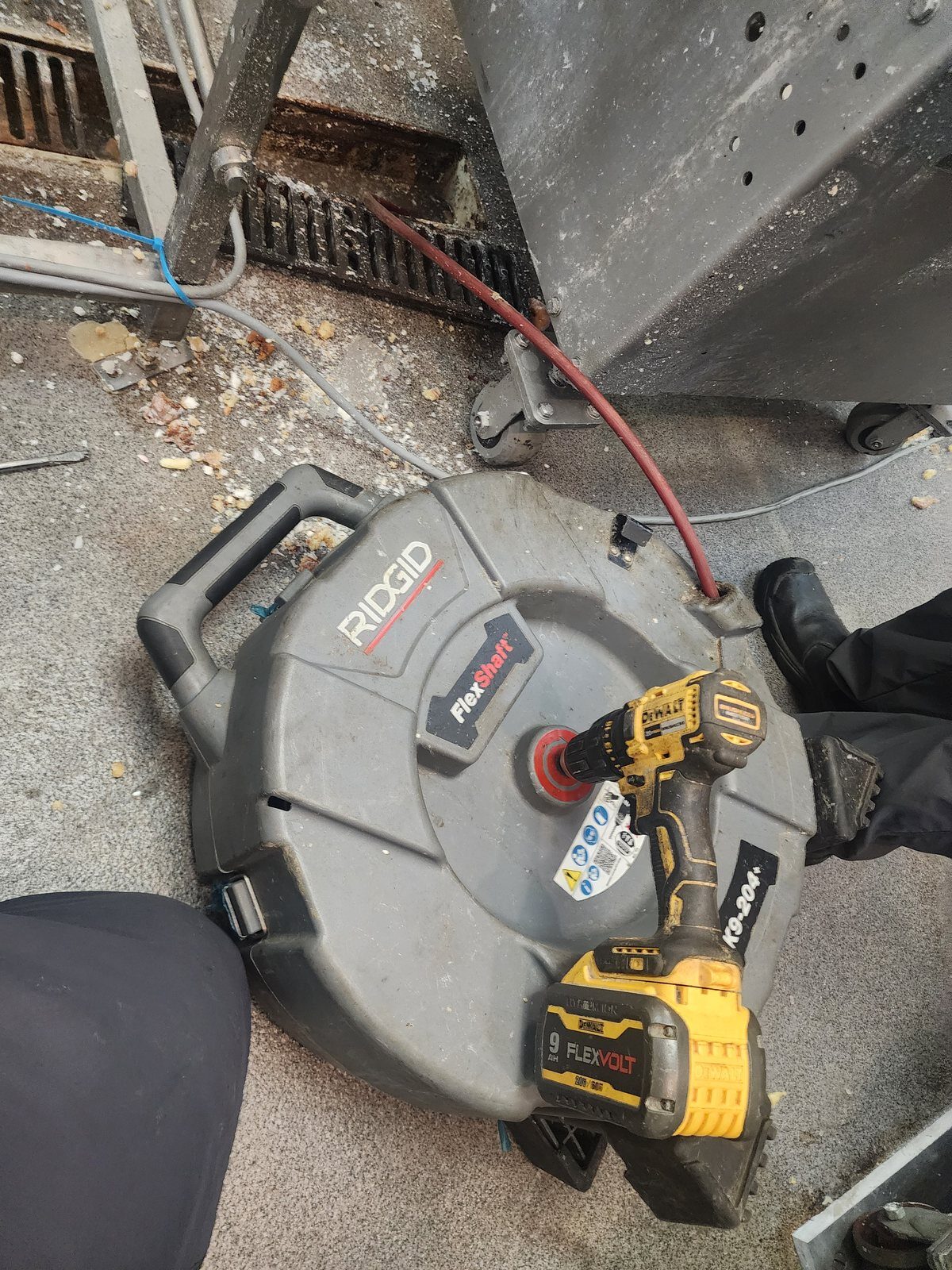 Clearing a blocked floor drain under commercial kitchen equipment