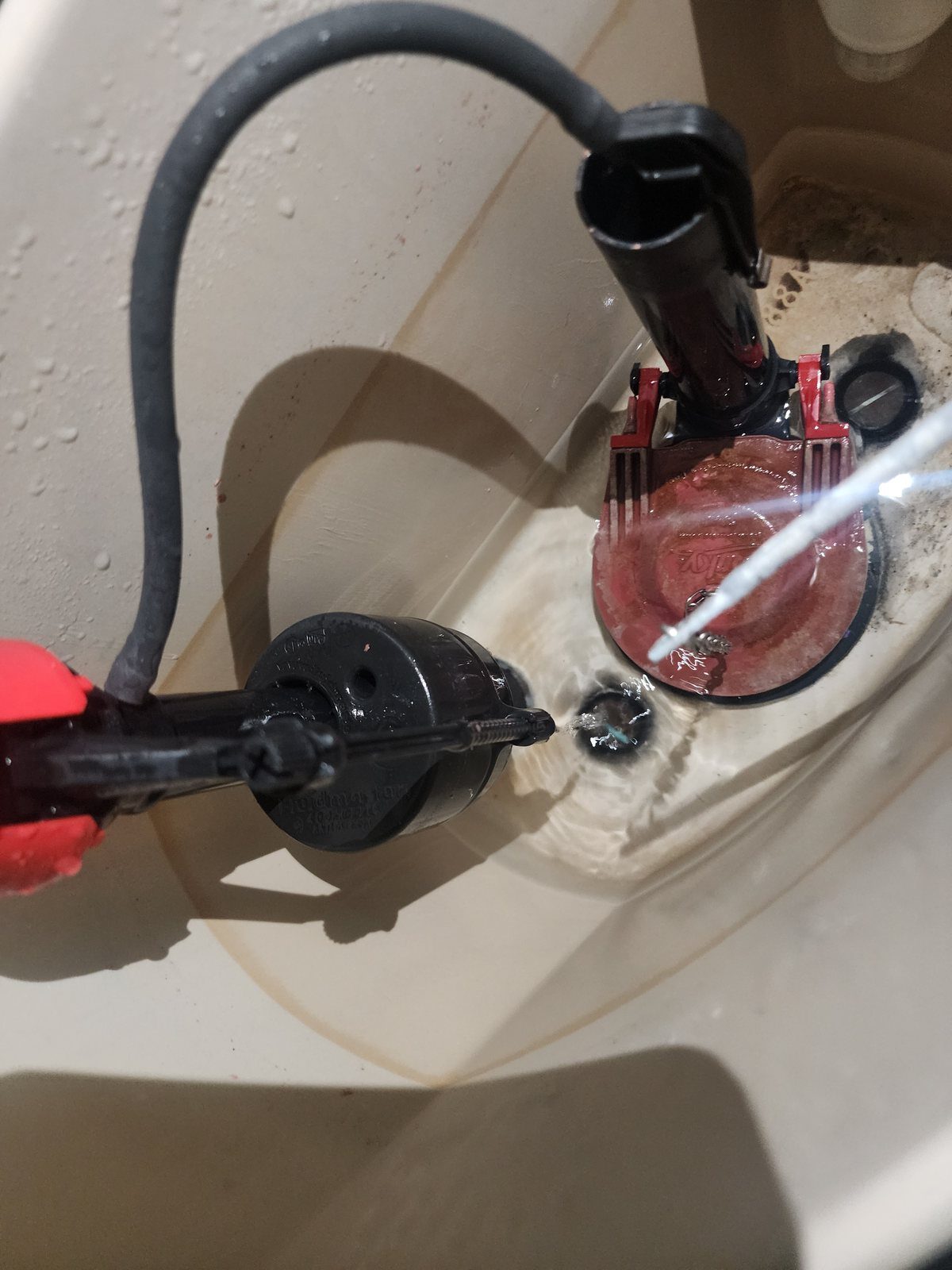 New toilet fill valve and flapper being installed in the tank
