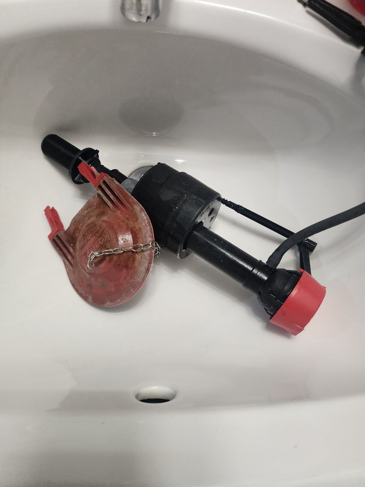 Old toilet fill valve and flapper removed showing mineral scale