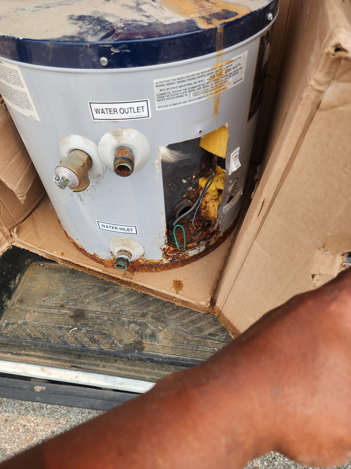 Old commercial water heater removed showing rust-through at the base