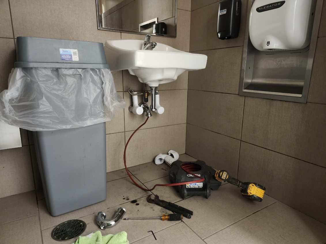 Commercial restroom sink drain cleared with a RIDGID drain machine
