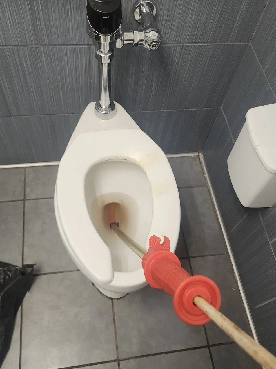 Clearing a clogged commercial toilet with a toilet auger