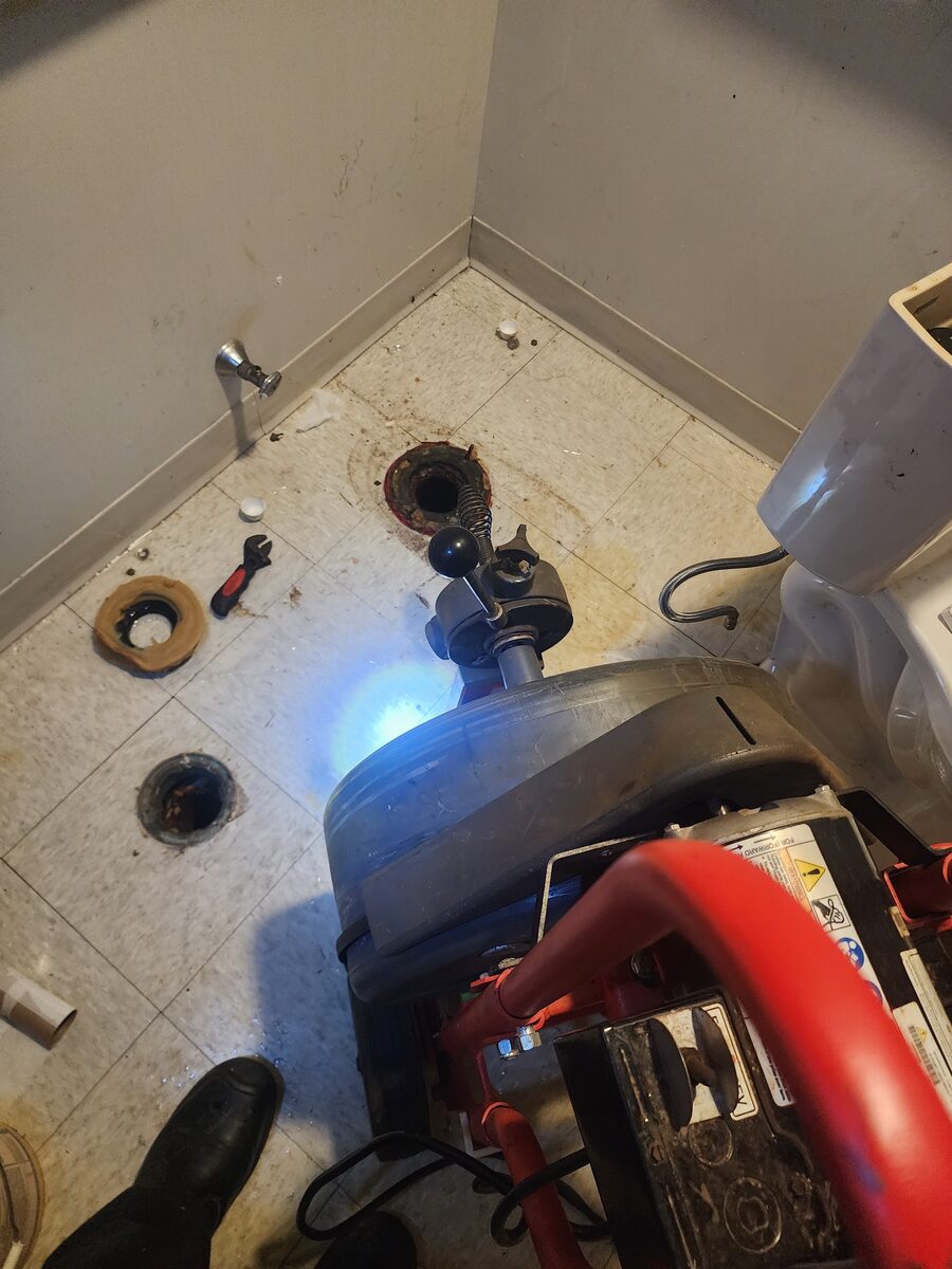 Toilet pulled to clear the line at the flange with a drain machine