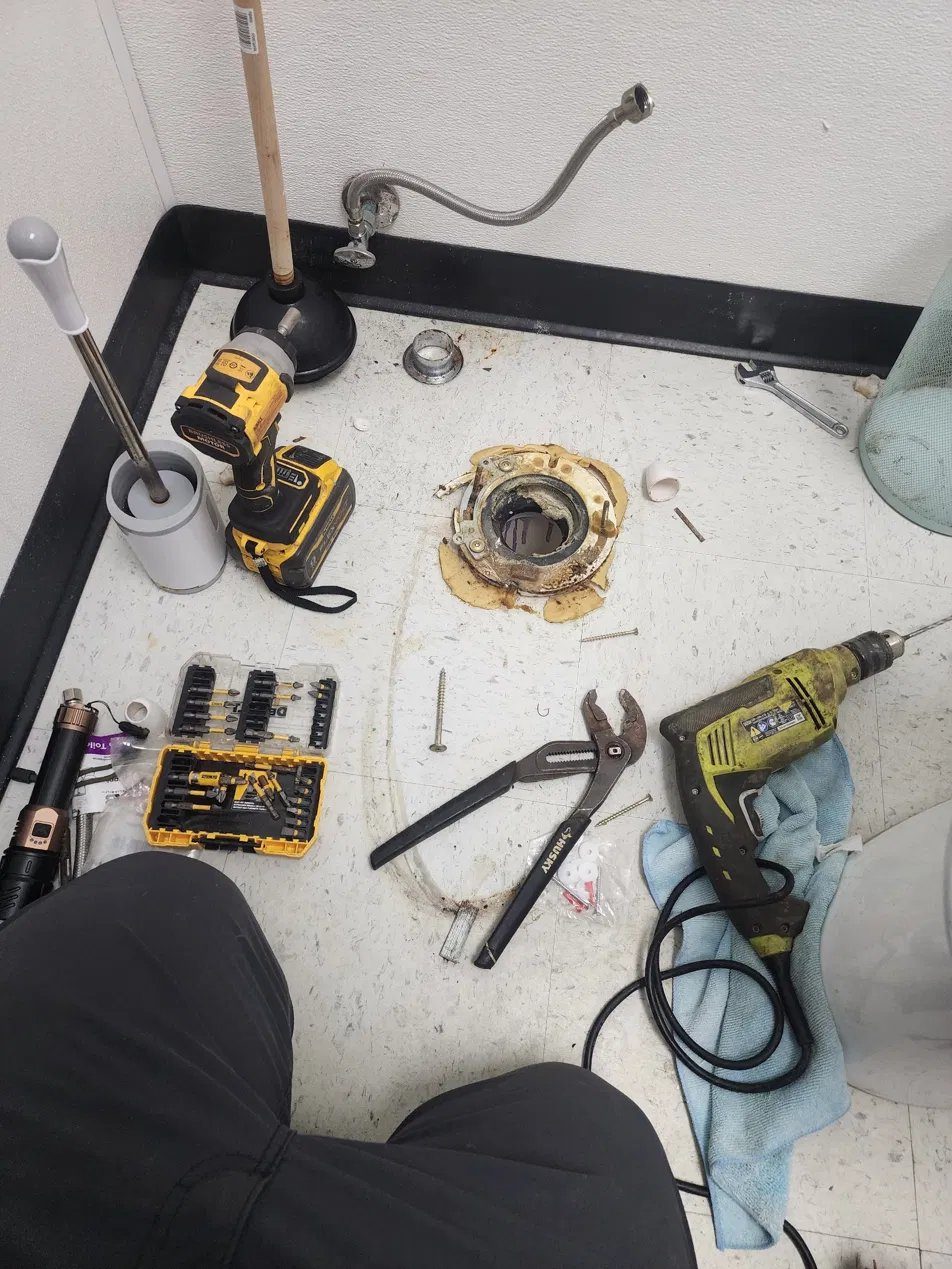 Toilet pulled and old flange exposed, with tools laid out for the reset
